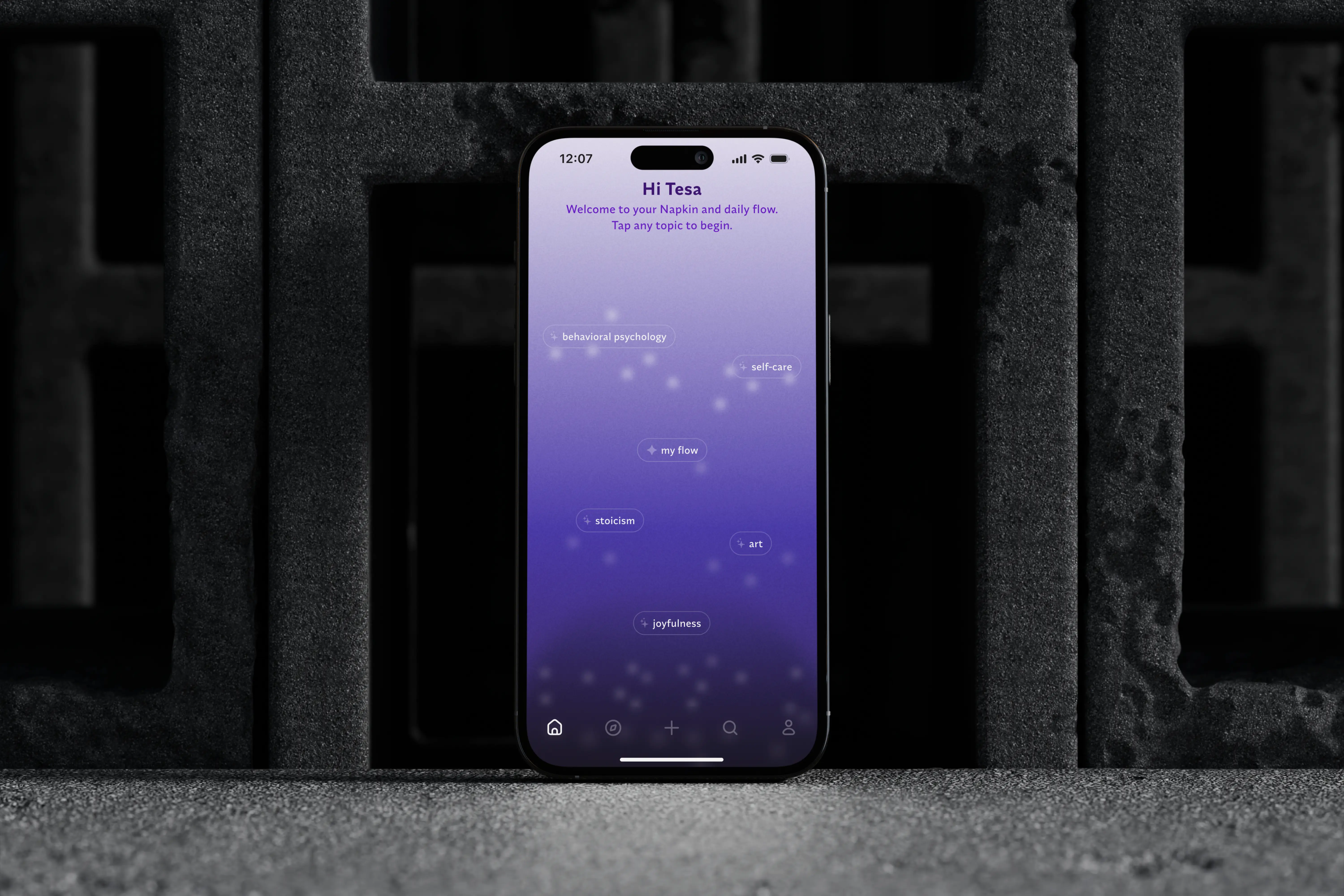 iPhone 16 displaying Napkin app "Home Screen" for topic exploration with topics like behavioral psychology, self-care, and joyfulness on a purple gradient background.
