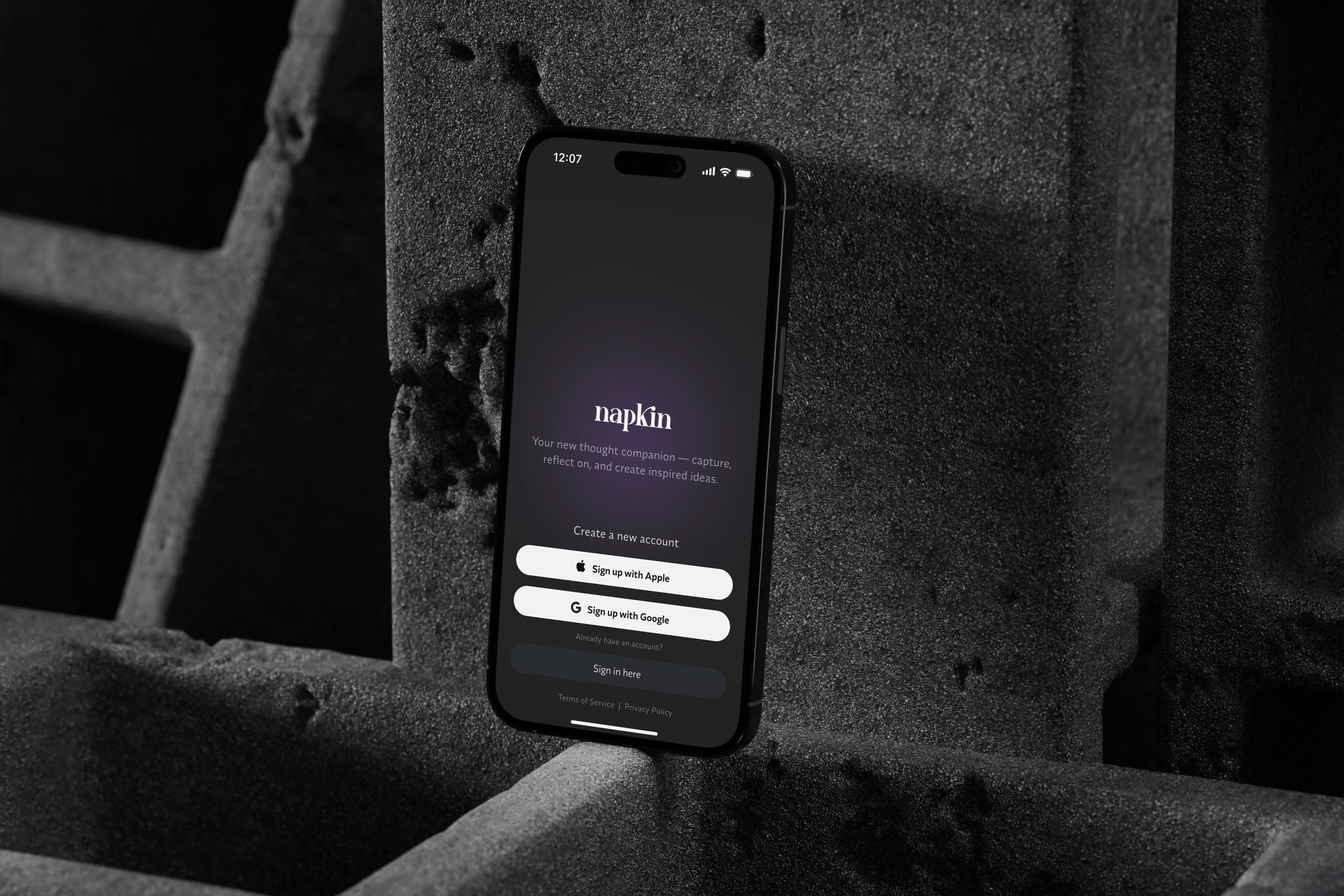 A iPhone 16 displays the Napkin app sign-up screen with options to sign up using Apple or Google.