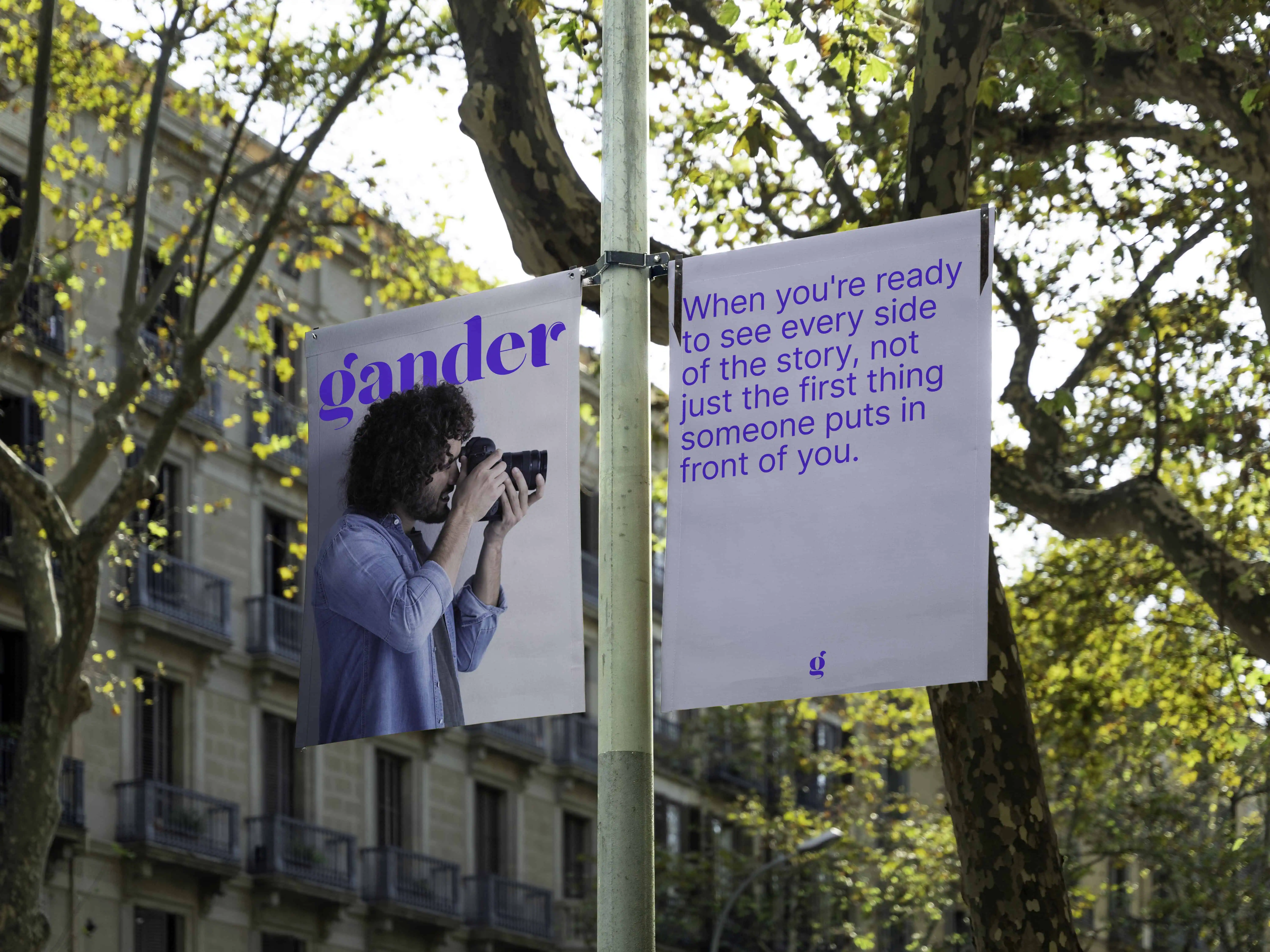 Two Gander street banners hang from a pole, one shows a man with a camera and the word Gander logo the other has a message reading "when you're ready to see every side of the story, not just the first thing someone puts in front of you."