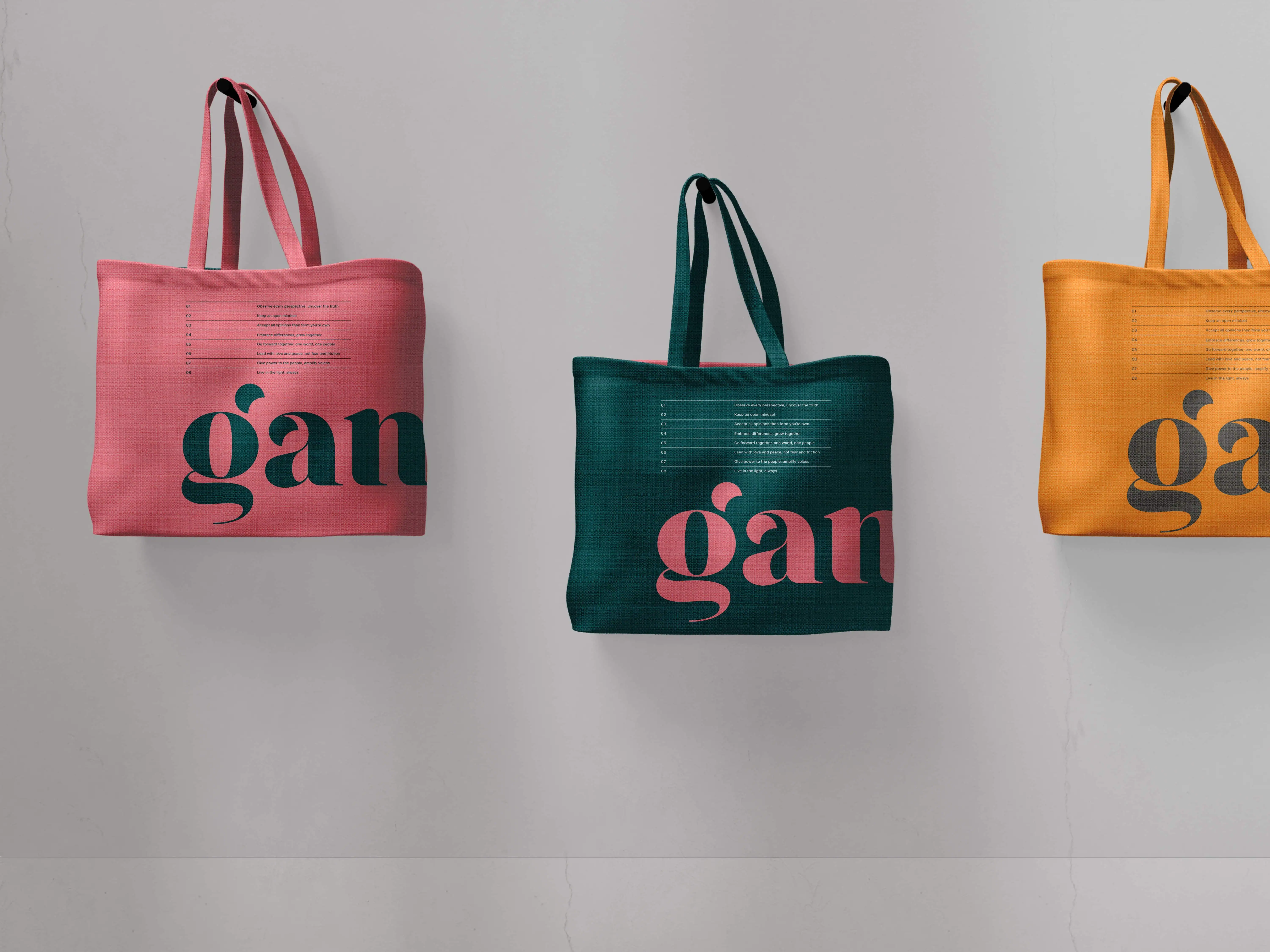Three colorful tote bags with contrasting wrap around Gander logo hang against a plain light gray wall.